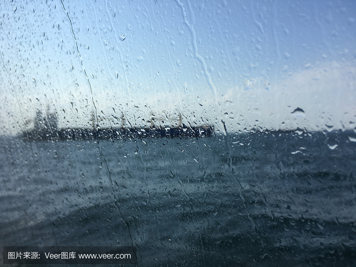 在潮濕的窗戶后面的海上油輪背景模糊圖像